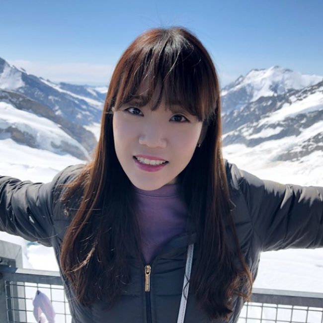 Headshot of Soyeon Kim in a purple top and black jacket. Snow mountains are in the background.