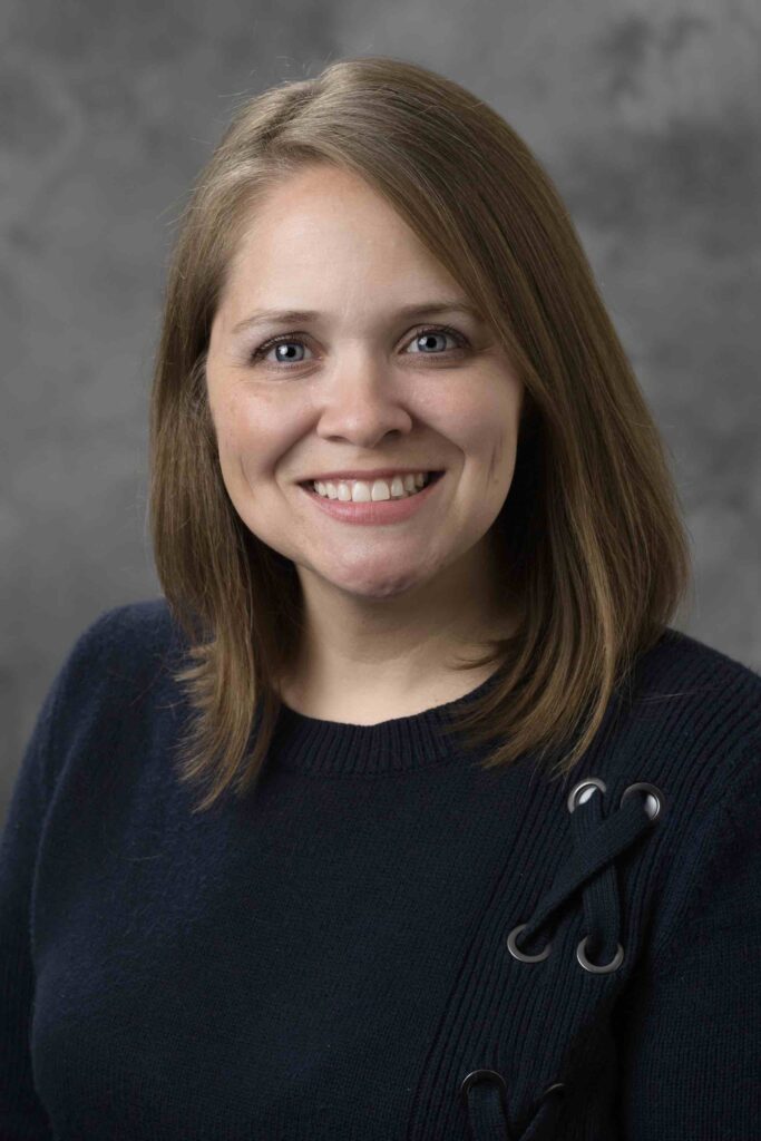 Headshot of Jennifer Smith with a black top against a grey background.