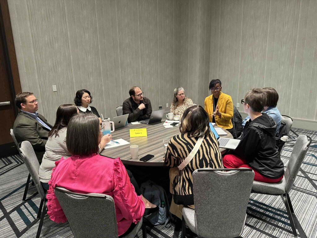 Conference attendees sitting at a roundtable to discuss a research study.
